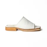 Zueco artesanal de cuero blanco, con diseño de pala ancha, punta cuadrada y suela plana con pequeño tacón de madera.