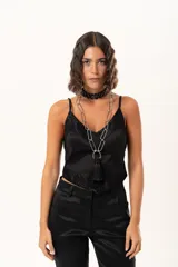 Top de satén negro con escote en V, decorado con detalles de encaje floral en el escote y en el ruedo. Presenta breteles finos ajustables y un corte asimétrico en la parte inferior.