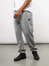 Pantalón de jogging de felpa con friza, color gris, con cintura elástica, bolsillos laterales y puños en los tobillos. Presenta un parche con el logo de Umbro en la parte superior delantera.