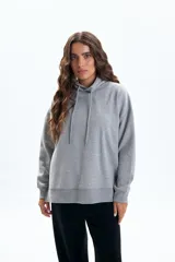 Canguro deportivo de corte holgado en color gris melange, con capucha ajustable mediante cordones y mangas largas con puños acanalados.