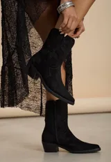 Bota texana de caña media confeccionada en gamuza negra, con diseño bordado en el empeine y la caña. Presenta taco cuadrado y cierre lateral interno.