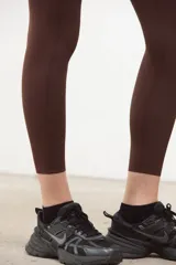 Calza deportiva de tiro alto color marrón espresso, confeccionada en tejido suave y elastizado con compresión media. Presenta un diseño sin costuras en el frente, largo 3/4 y terminaciones con corte láser en las piernas.