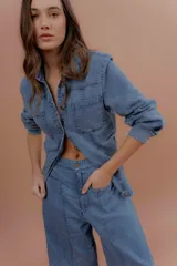 Chaqueta de jean azul, de corte entallado, con cuello camisero, cierre frontal con botones y bolsillos delanteros con solapa.