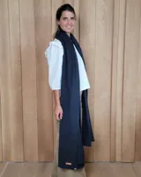 Bufandón de lana lambswool, de textura suave y liviana, con diseño liso y etiqueta de cuero en el extremo inferior.