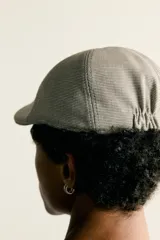 Boina con visera de color beige y marrón con diseño de cuadros pequeños, confeccionada en tejido con viscosa y ajuste elástico posterior.
