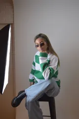 Sweater blanco con rayas horizontales verdes, de corte holgado y mangas largas.