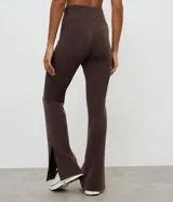 Pantalón deportivo de corte flare, color marrón, con cintura elástica y diseño liso. Presenta una abertura lateral en el bajo.