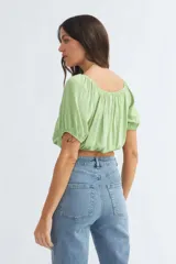 Blusa roja con escote cuadrado, mangas cortas abullonadas y cierre frontal con botones.