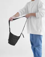 Bandolera celeste acolchada con correa larga ajustable de cinta negra.