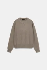 Jersey de punto liso con cuello redondo y manga larga, con detalle de costura en forma de V en el cuello.