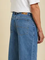 Jean de corte loose fit, confeccionado en algodón, con diseño de cinco bolsillos y cierre frontal con botón y cremallera.