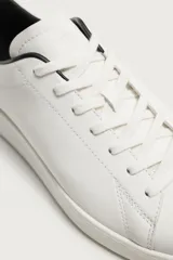 Zapatilla de cordones con parte superior fabricada en piel, de horma redonda y suela a tono.