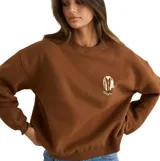 Buzo Rhythm Sunny Crew Neck Fleece de color marrón, cuello redondo, mangas largas y calce holgado. Cuenta con un pequeño estampado en el pecho.