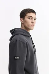 Canguro con capucha y cordones ajustables, confeccionado en algodón con detalle de estampado frontal en tonos verdes. Presenta un bolsillo tipo canguro delantero, puños y ruedo acanalados.