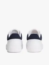 Zapatillas de tenis minimalistas Tommy Hilfiger, confeccionadas en piel napa blanca con suela gruesa tipo cupsole. Presentan un diseño de corte bajo con cordones, detalle de panel azul marino en el talón y logo metálico de la marca en el lateral.