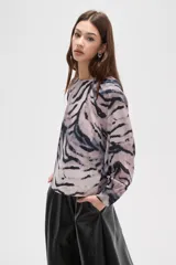 Blusa de manga larga con estampado animal print abstracto en tonos grisáceos y negros. Presenta cuello a la base y cierre con botón en la parte posterior.