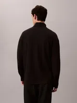 Remera de manga larga con cuello alto tipo tortuga, confeccionada en tejido de punto ponte. Presenta un diseño minimalista con logo de la marca bordado discretamente en el cuello.