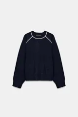 Jersey de punto de manga larga con cuello redondo, diseño en color azul marino con detalles de vivo en color blanco en el cuello y las costuras de las mangas.