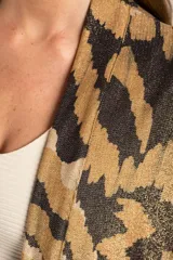 Kimono con estampado abstracto en tonos marrón, beige y negro. Tiene mangas 3/4 y bolsillos laterales.