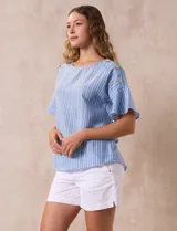 Blusa de mangas cortas amplias con aplique de botones en los hombros. Diseño a rayas verticales celestes y blancas.