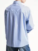 Camisa de corte clásico con estampado de rayas verticales azules y blancas, cuello camisero y cierre frontal con botones. Incluye una corbata a juego con el mismo estampado.