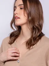 Cárdigan corto color beige, de manga larga y escote en V. Tiene cuatro botones brillantes.