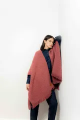 Ruana color rosa viejo de tejido de punto grueso con flecos en el borde inferior.