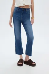 Pantalón jean de corte recto y tiro alto, en color azul, con diseño clásico de cinco bolsillos y terminación desmechada en los tobillos.