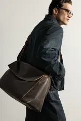Bandolera XL de piel color marrón oscuro con acabado desgastado, compartimento principal con solapa y cremallera, y correa de hombro ajustable con hebilla.