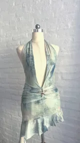 Vestido corto de microtul celeste con efecto tie-dye en tonos verde agua y gris. Diseño halter con escote profundo en V, fruncido en la cintura con un aplique de estrella de mar brillante, y ruedo con volado.