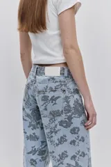 Jean de tiro medio con calce amplio y piernas wide leg, confeccionado en denim celeste con estampado floral. Cuenta con diseño de cinco bolsillos y cierre frontal con botón y cremallera.