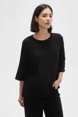 Remera de viscosa en color verde oliva, con cuello redondo y mangas 3/4. Presenta un diseño de tejido acanalado y corte holgado.