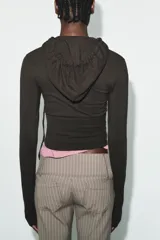 Sudadera cropped de punto con cierre frontal de cremallera metálica, capucha ajustable con cordones y mangas largas con puños en rib.