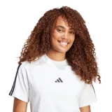 Remera de algodón blanca con cuello redondo, mangas cortas y las icónicas tres tiras de la marca en color negro sobre los hombros. Presenta el logo de Adidas bordado en el centro del pecho.