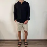 Camisa de manga larga confeccionada en muselina de algodón, con cuello mao y cierre frontal de tres botones. Presenta una textura arrugada característica del tejido y puños con opción de arremangar.