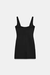 Vestido corto de tejido de punto elástico, con escote redondo, tirantes anchos y costuras marcadas que definen el busto. Presenta un diseño ajustado con cierre lateral oculto.