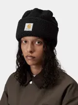 Gorro tipo beanie Carhartt modelo Prentis, confeccionado en tejido de pelo sintético texturizado color negro. Presenta un diseño con vuelta y etiqueta cuadrada con el logo de la marca en la parte frontal.