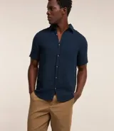 Bermuda básica masculina confeccionada en sarga de algodón, de corte recto con trabillas en la cintura, bolsillos y cierre frontal con botón y cremallera.