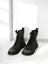 Borcego de cuero color gris desgastado, con cordones negros, cierre interno y suela track.