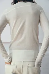 Jersey de punto fino con diseño color block en tonos rojo, bordó y blanco. Presenta cuello redondo y manga larga.