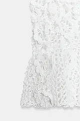 Top de crochet color blanco con diseño de flores tejidas, escote redondo y tirantes finos.