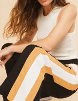 Pantalón palazzo color beige con cintura elastizada y dos franjas verticales en los laterales, una plateada y otra blanca.