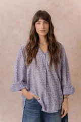 Camisa lila oversize de algodón con bordado floral calado tipo broderie, cuello camisero, manga larga y abotonadura frontal.