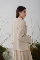 Sweater beige de tejido de punto acanalado con cuello redondo y mangas largas. Presenta apliques de manchas de colores en el frente y las mangas.