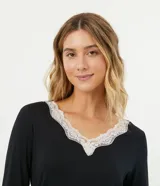 Conjunto de pijama negro de dos piezas, compuesto por una blusa de manga larga con escote en V y detalle de encaje blanco, y un pantalón largo de corte recto con cintura elástica.