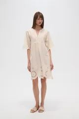 Vestido corto color crema, con escote en V y mangas 3/4. Presenta detalles de bordado inglés (broderie) en el canesú superior y en el ruedo inferior.