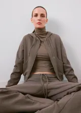Campera con capucha y cierre frontal de cremallera, de color gris topo, con bolsillos canguro y diseño corto.