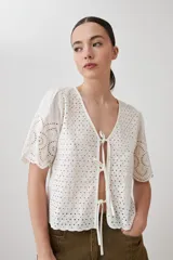 Blusa negra de broderie con escote en V y lazos para atar en el frente. Tiene mangas cortas con terminación de puntilla. 