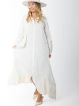 Maxi vestido camisero de lino blanco con bordados en tono beige en mangas y ruedo. Presenta cuello camisero, botones frontales y mangas largas.