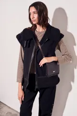 Chaleco negro con cuello de piel sintética, cierre frontal con cremallera y corte oversize.